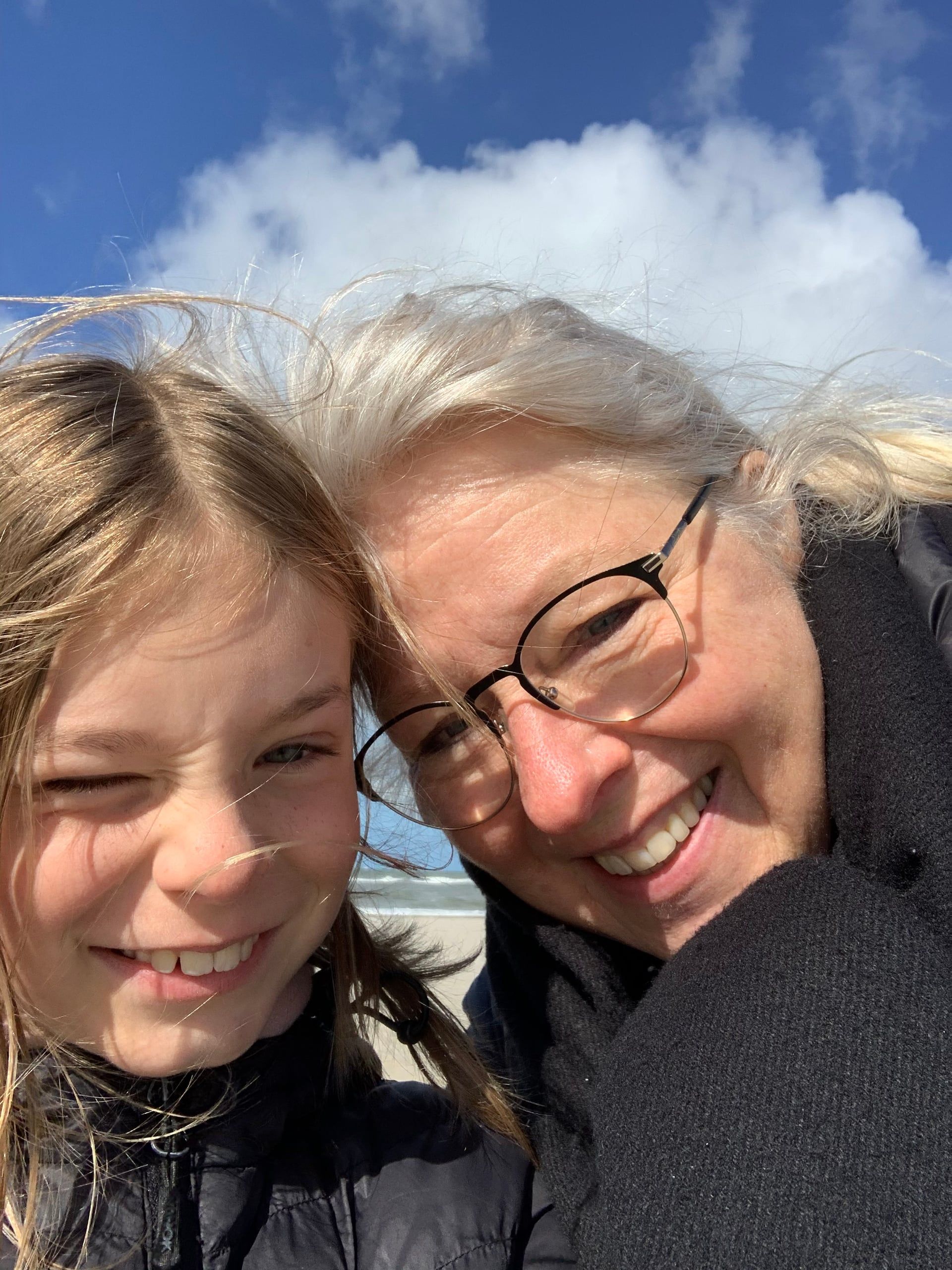 Naja og hendes mormor griner i blæsten på stranden